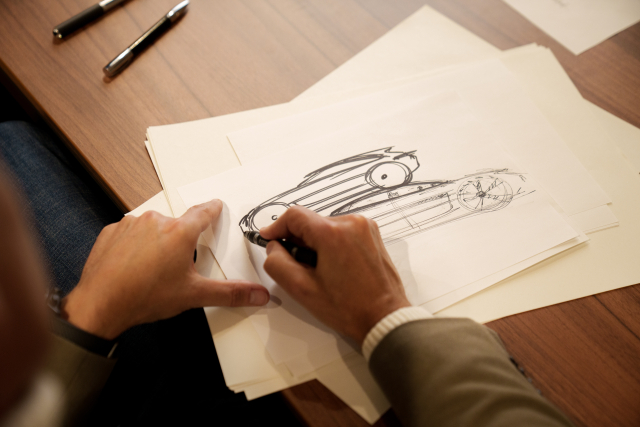 Michael Mauer drawing the side view of a car on a piece of paper