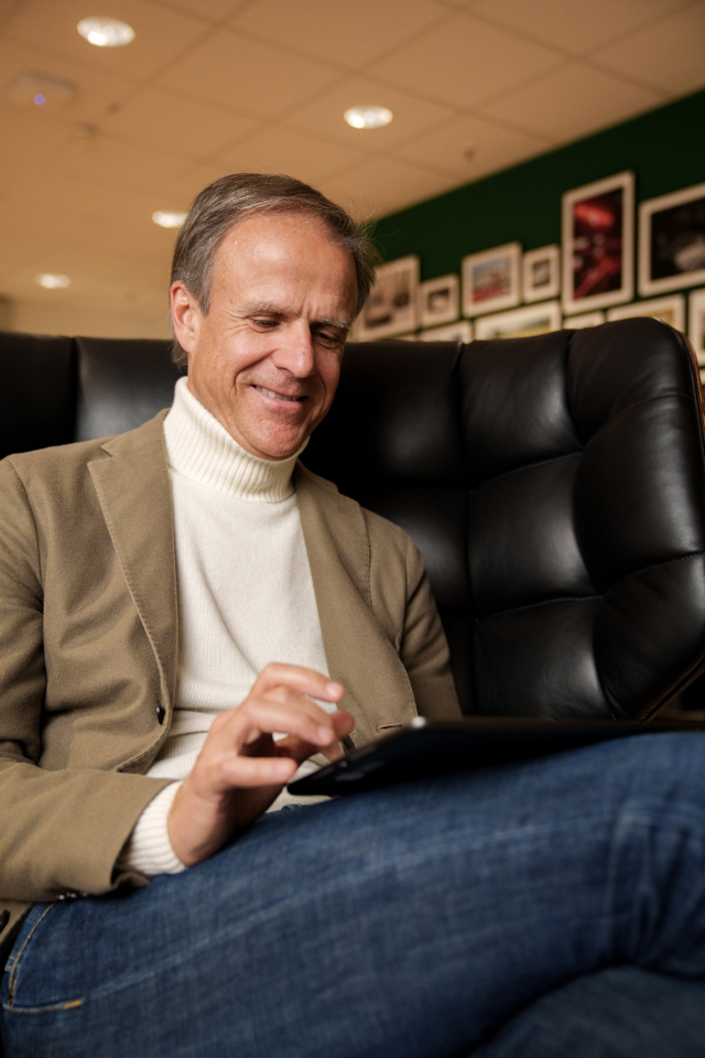 Michael Mauer sitting on an armchair with a tablet in his hands smiling